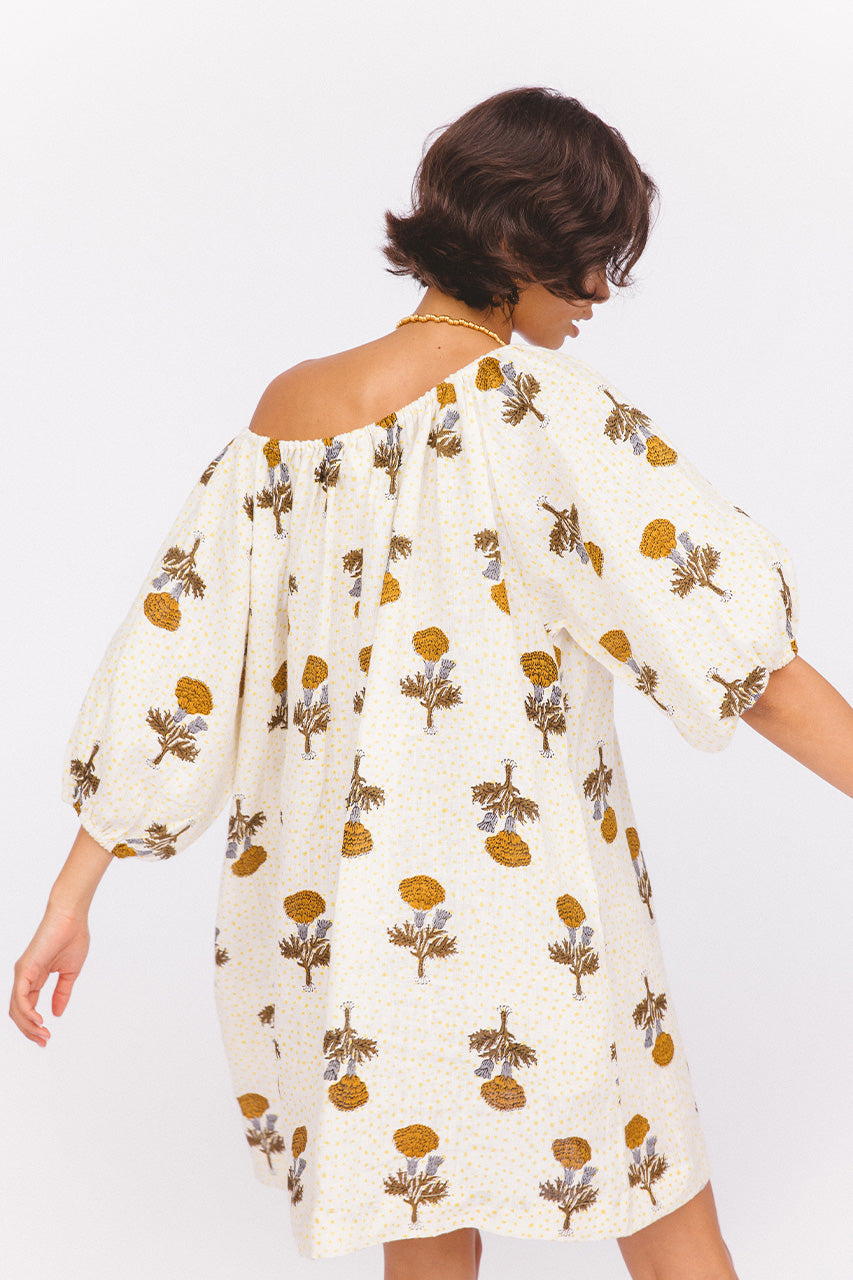 Dahlia Mini Dress Marigold — back side profile, off-shoulder showing back neckline, billowy sleeve detail, white cream linen with golden marigold botanical hand block print, artisan boho dress | Daughters of India