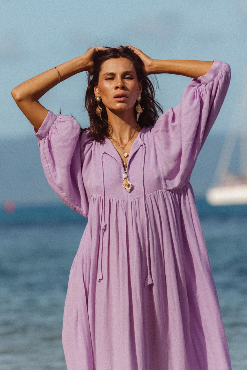 Daughters of India Kyra Midi Dress in Lilac Gauze — close-up V-neckline on beach, billowed sleeves, shell necklace
